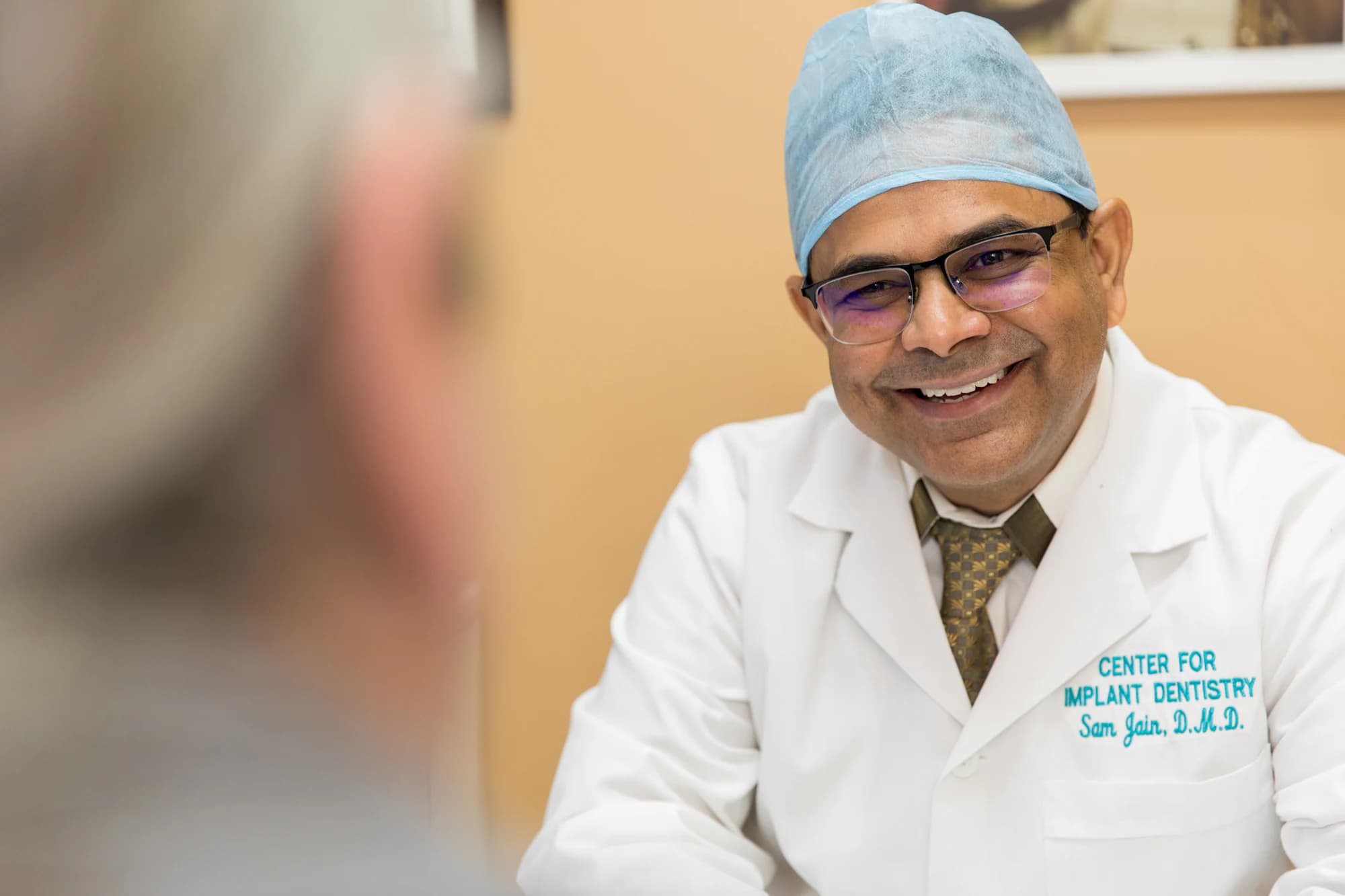 Dr. Sam Jain smiling with a patient during an implant consultation